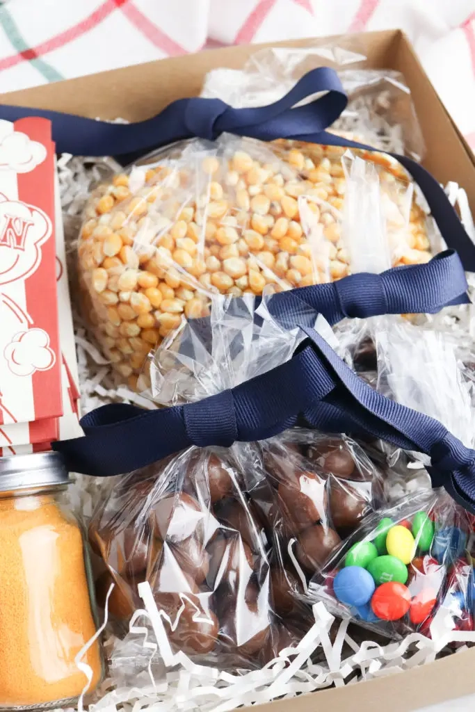 Filmavondje in een doos gevuld met een popcornzakje, kruidenzout, pitten en snoep.