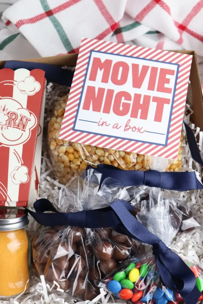 Filmavondje in een doos gevuld met een popcornzakje, kruidenzout, pitten en snoep.
