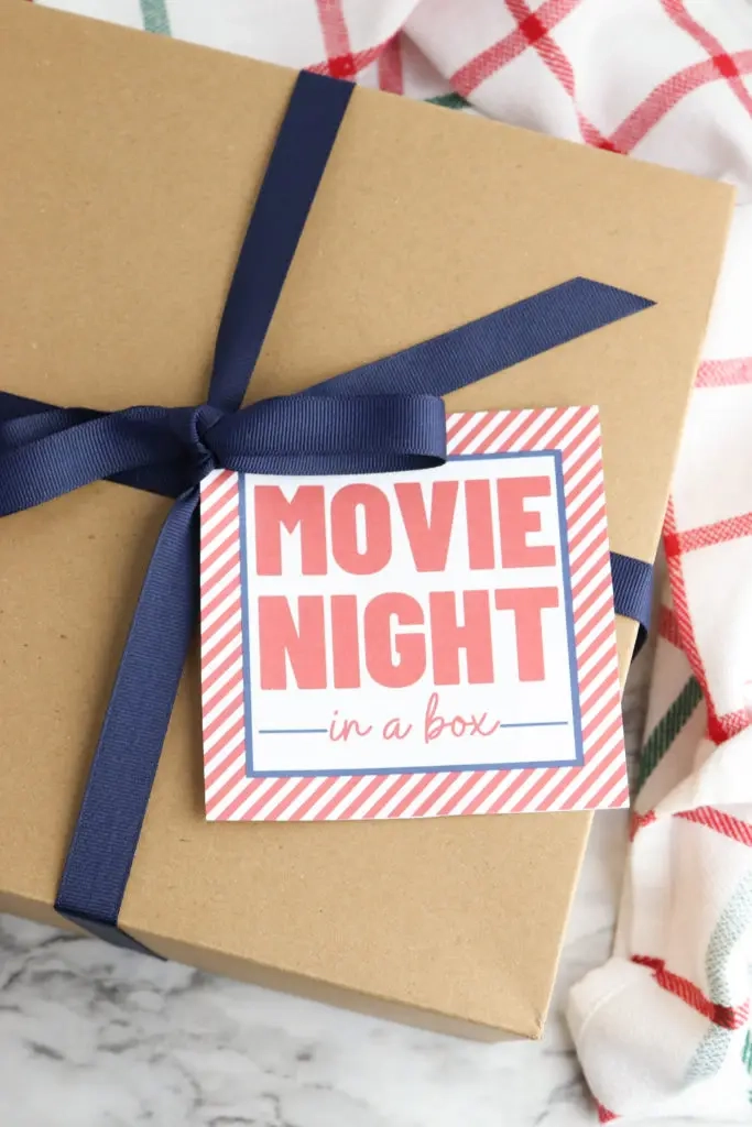 Kartonnen doos omwikkeld met lint en een printbaar cadeaukaartje voor een filmavond.